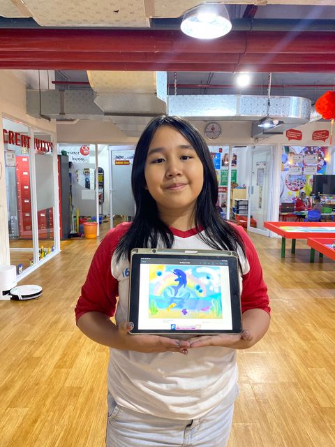 A student holding up a tablet showing her digital painting