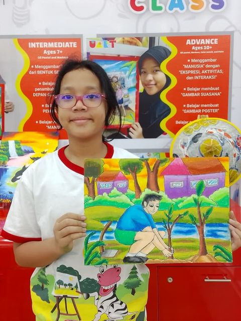 A student in front of a Uart class poster holding up her colourful painting
