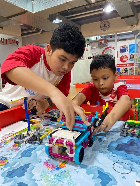 Two students building a LEGO robot together on a challenge mat
